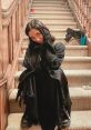 Young woman in black attire poses on staircase, capturing a playful moment inspired by Amber from Scream 5.