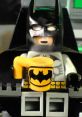 Lego Batman holds a yellow mug with an iconic logo, ready for action amid the backdrop of a futuristic setting.