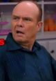 Red Forman shows a shocked expression while wearing a blue shirt, capturing his iconic character's comedic moments.