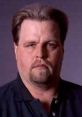 Mark Madden's stern expression, showcasing a serious demeanor and distinctive style in a close-up portrait.