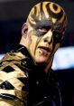 Goldust showcasing his iconic face paint and elaborate costume during a wrestling match in a dynamic pose.