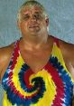 Dusty Rhodes smiling in a colorful tie-dye tank top, showcasing his iconic wrestling persona and charisma.