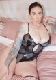 Paige Turnah showcases confidence in a striking black mesh bodysuit, accentuating her unique tattoos and seductive pose.