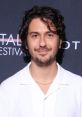 Nat Wolff smiling at a film festival, showcasing his trendy style, a rising talent in entertainment and AI voice projects.
