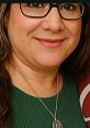 Portrait of Lorraine Flores wearing glasses and a green top, showcasing her friendly smile and silver jewelry.