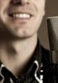 Smiling man with deep voice singing into a microphone, showcasing vocal talent and passion for music.