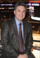 Nick Nickson smiling in a sports arena, wearing a suit and tie, showcasing his passion for hockey broadcasting.