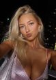 Sydney Thomas showcases a glamorous night look with sparkling attire and city lights in the background, radiating confidence.
