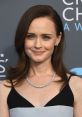 Alexis Bledel, known for her role as Rory Gilmore, smiles elegantly, showcasing her classic style and stunning blue eyes.