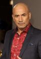 Temuera Morrison in a stylish outfit, showcasing his signature look with a confident expression at a red carpet event.