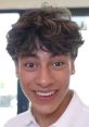Cheerful young man with curly hair showcases an animated expression, capturing a lively moment in a bright setting.