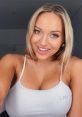 Erna Husko poses with a bright smile in a casual gray tank top, showcasing her confident personality and striking features.