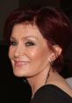 Sharon Osbourne smiling with stylish short hair and earrings, showcasing her glamorous and confident personality.