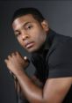 Kel Mitchell poses stylishly in a black shirt, showcasing a confident look reminiscent of his 1999 fame.