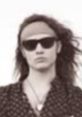 Vintage-style portrait of a young man with long hair, sunglasses, and a bandana, exuding a laid-back Bunbury vibe.