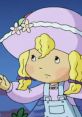 A young girl with blonde curls in a pink hat gestures thoughtfully, capturing the whimsical spirit of Angel Cake.