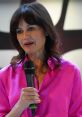 Carla Gugino speaks passionately into a microphone, wearing a vibrant pink blouse, showcasing her captivating presence.