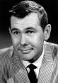 Johnny Carson smiles in a striped suit, exuding charm and charisma, emblematic of classic late-night television.