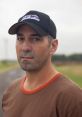 Sean Casey, a storm chaser, looks focused, wearing a cap and casual shirt against a cloudy backdrop.