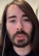 Portrait of a young man with long dark hair and a beard, speaking intently, embodying a thoughtful demeanor.