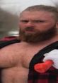 Muscular man with a thick beard, wearing a flannel shirt and holding an orange tool, embodies the spirit of the Greenboro Bear.