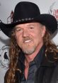 Trace Adkins smiles confidently in a cowboy hat, showcasing his signature style at a public event.