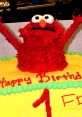 Elmo birthday cake with colorful decorations, featuring playful red frosting and a cheerful "Happy Birthday" message.