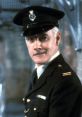 Mr. Mackay from Porridge in a classic prison officer uniform, showcasing a stern expression and authoritative demeanor.