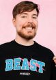 MrBeast smiles while wearing a black shirt with a colorful "BEAST" logo, showcasing his gaming brand's style.