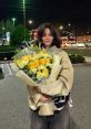 Maddie Jackson smiles while holding a large bouquet of yellow flowers on a city street at night.