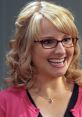 Bernadette Rostenkowski smiling, wearing glasses and a pink cardigan, showcasing her cheerful personality from The Big Bang Theory.