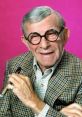 George Burns smiling with a cigar, wearing glasses and a checkered suit, set against a vibrant pink background.