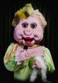 Madame Oink in glamorous attire, holding a microphone, exudes charm and personality, captivating the audience.