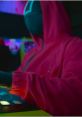 Female announcer in Squid Game - The Challenge, wearing a pink hoodie and interacting with game controls.