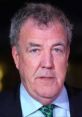 Jeremy Clarkson with a serious expression, wearing a dark suit and patterned tie, at a formal event.