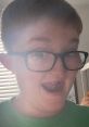 Joyful boy with glasses making a funny face, showcasing personality and enthusiasm in a brightly lit room.
