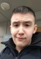 Portrait of a young boy named YARIK, wearing a black jacket, with a thoughtful expression and short hair outside a building.