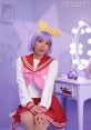 Tsukasa Hiiragi cosplay by Momo Kariño, featuring a vibrant purple wig and a cute school uniform in a pastel setting.