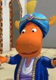 Sultan Tyrone from Backyardigans, dressed in vibrant attire, welcomes guests with a joyful expression in a colorful setting.