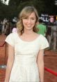 Elissa Knight smiling on the red carpet, wearing a stylish white dress at a film premiere event.