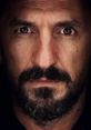 Intense portrait of a man with a beard, capturing the essence of strength and resilience, reflecting Xhevdet Jhevdo Jashari.