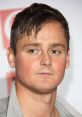 Tom Chaplin at a red carpet event, showcasing his distinctive hairstyle and expressive eyes. Keane's lead vocalist.