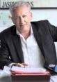 Alberto Olivero smiling at his desk with documents, showcasing professionalism and a collaborative work environment.