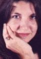 Close-up of a woman thoughtfully resting her hand on her chin, with warm expressions and natural beauty.