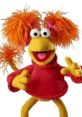 Red Fraggle from "Fraggle Rock" smiles energetically, showcasing her vibrant orange hair and red sweater.