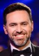 Timur Miroshnychenko smiling in a stylish tuxedo, showcasing his charm at an entertainment event.