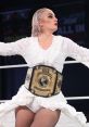 Toni Storm showcasing her AEW Women's World Championship in an elegant white outfit during an intense wrestling event.
