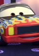 Darrel Cartrip from Cars 2006, featuring vibrant flames on a red car, showcasing his playful personality at a racing event.