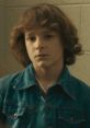 Finney from "Finney Evil 48," looking contemplative in a denim jacket, showcasing a vintage fashion style.