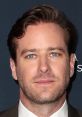 Armie D. Hammer attends a red carpet event, showcasing his blue eyes and styled hair with a sophisticated outfit.